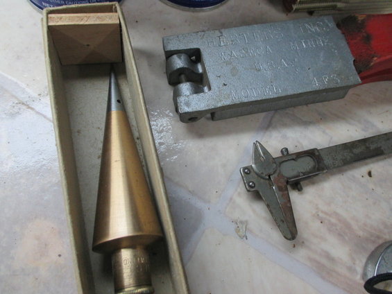 Plumb bob in a box next to a metal mold and calipers