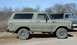 1978 Ford Bronco - This 1978 Ford Bronco, painted in a camouflage pattern, is seen parked outdoors next to another truck.