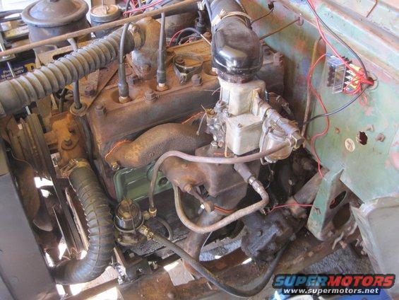 Close-up of a rusty Jeep engine with hoses, carburetor, and wiring visible