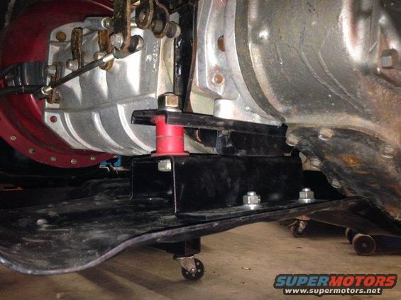 Transmission mount assembly with red and silver components, bolted to a black metal bracket on casters