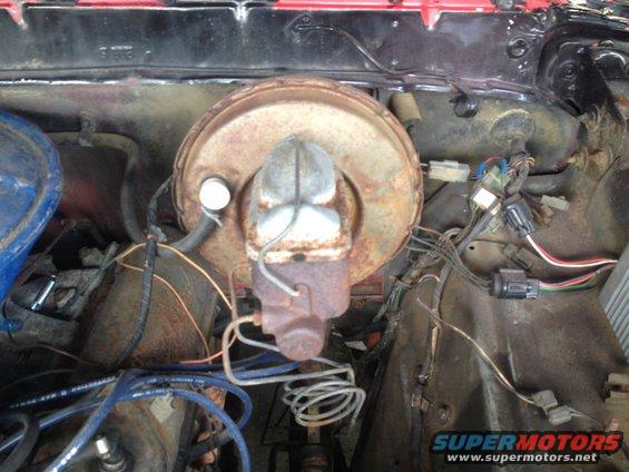 Rusty brake booster and master cylinder assembly with wiring harness in engine bay