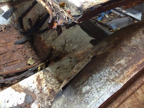 Heavily rusted vehicle interior with exposed metal and debris
