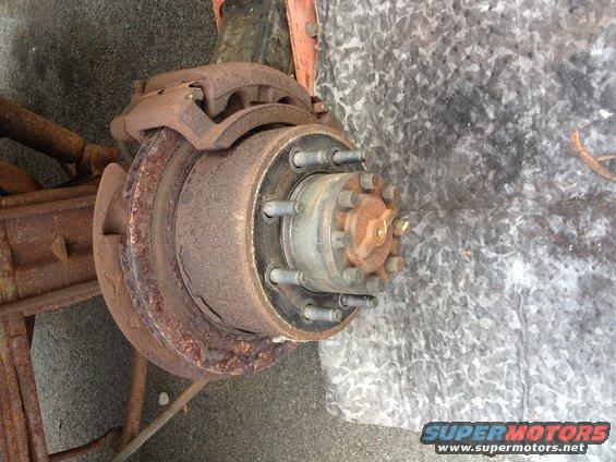 Rusted brake rotor and hub assembly with multiple lug nuts and brake caliper