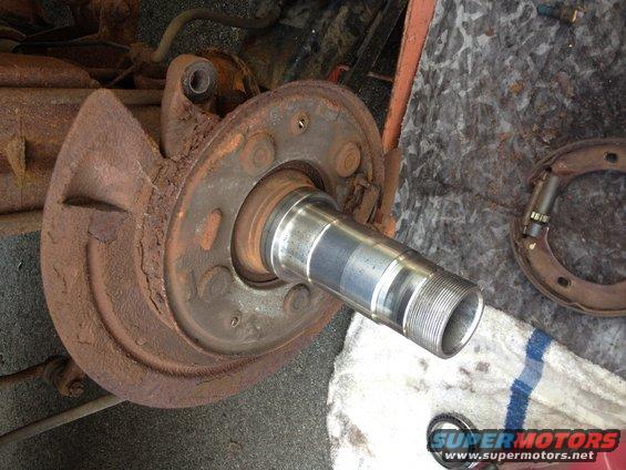 close-up of rusty wheel hub, brake drum, and spindle with threads