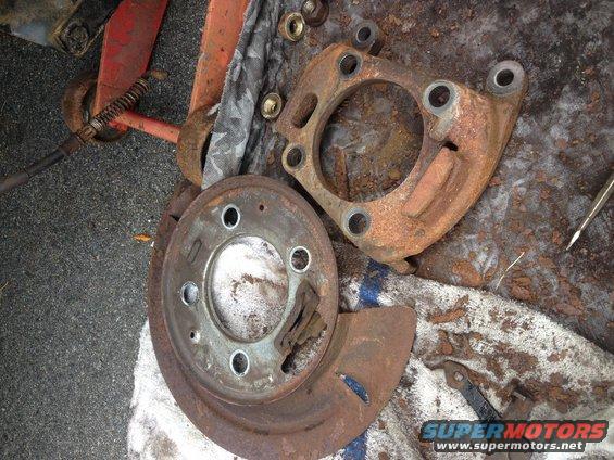 Rusted brake rotor and caliper bracket with nuts on a cloth