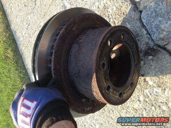 Rusted brake rotor and hub assembly held by gloved hand