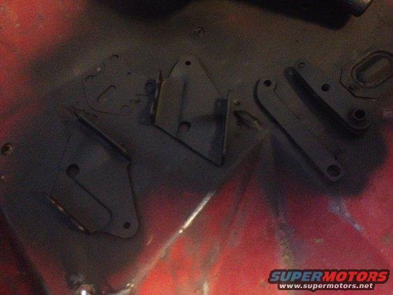 Black painted metal brake brackets on a red surface