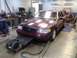 2004 Ford Crown Victoria - A maroon 2004 Ford Crown Victoria is positioned on a dynamometer in a workshop setting.