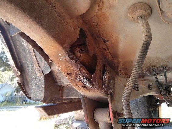 rusted frame section with holes, wire loom, and part of a tire visible