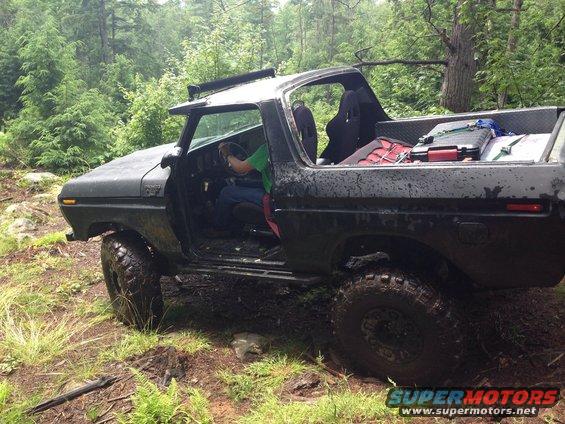 Black Ford Bronco with lifted suspension and off-road tires stuck in mud, driver inside
