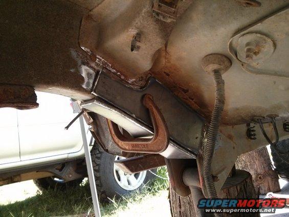 Frame repair with C-clamp and metal plate, white SUV visible