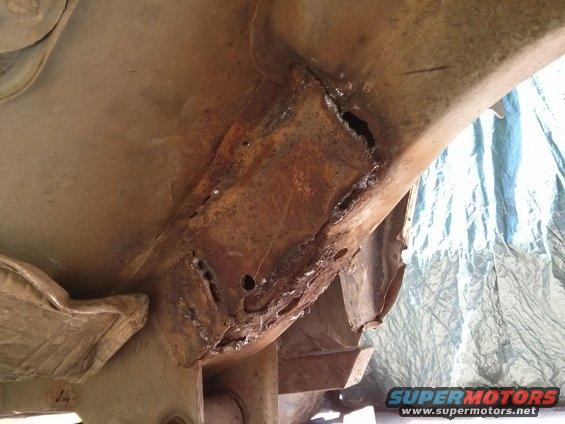 Heavily rusted frame section with holes and visible weld repairs