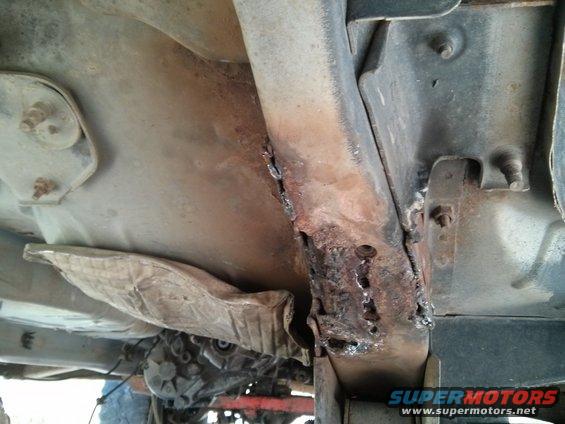 rusted out frame rail on a vehicle, showing extensive corrosion and repair welds