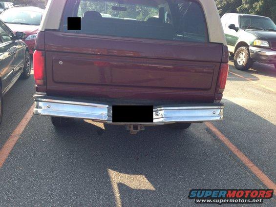 Rear of maroon Ford Bronco with tan top, parked next to other vehicles
