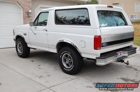 White Ford Bronco parked in driveway, rear quarter view. Has 4x4 badge on fender
