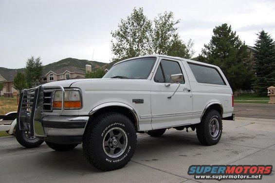 White Ford Bronco with brush guard, chrome trim, and BFGoodrich tires parked on a driveway