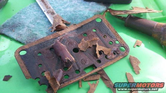 worn gasket on green surface with a screwdriver and a tool