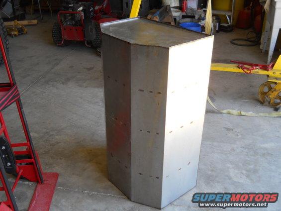 Hexagonal metal object in garage with "Supermotors.net" logo