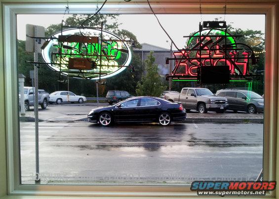 Side view of a black 2002 Chrysler 300M parked on a wet street