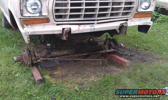 Front end of a truck, possibly 1970s Ford F-Series, with the entire front suspension and steering assembly removed and resting on blocks