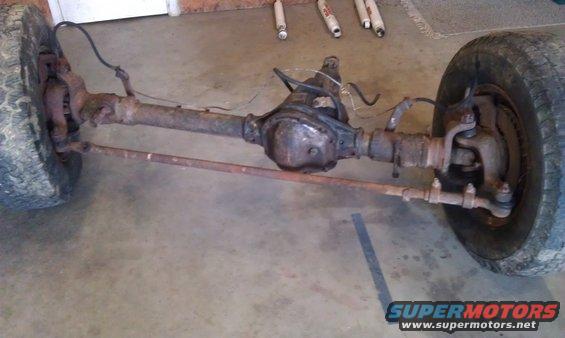 Front axle assembly with tires, brake drums, and steering linkage