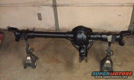 Black rear axle assembly on jack stands in a garage