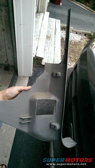 Gray plastic interior trim panel with cutouts and mounting points, held by a hand