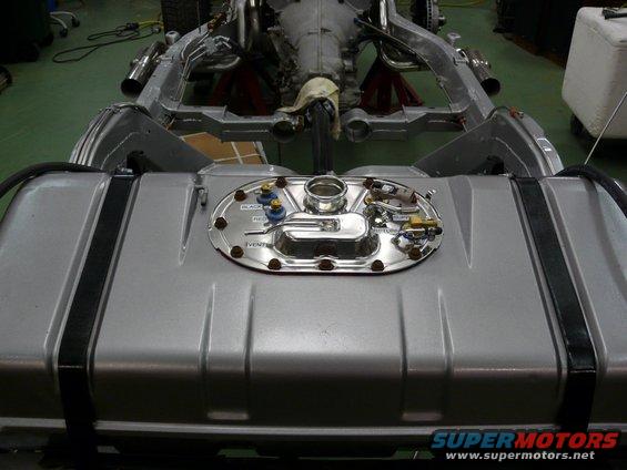 Silver fuel tank with chrome sending unit and fittings, part of a vehicle chassis visible above