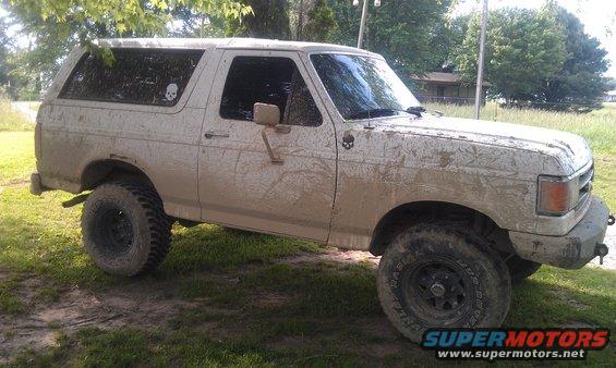 Mud-covered 1990 Ford Bronco parked on grass, side view