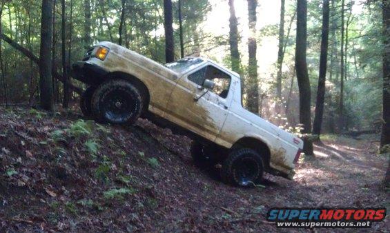 White pickup truck on a muddy incline in a forest