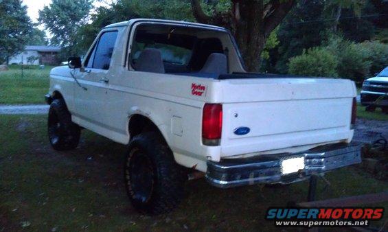 White Ford Bronco with lifted suspension and off-road tires parked in a grassy area