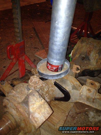 Rusty axle parts and a metal pipe on jack stands