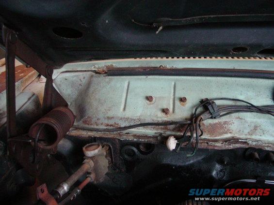 Car's firewall under the hood, showing rust and some wiring