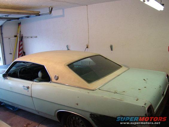 1969 Ford Torino coupe with a light-colored vinyl roof, seen from the rear quarter in a garage