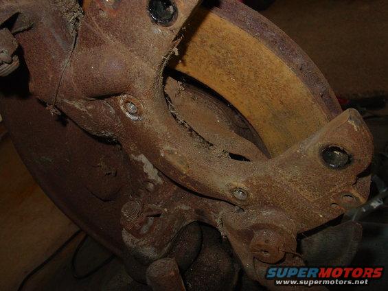 Heavily rusted brake caliper and rotor assembly, close-up view