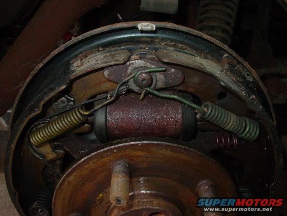 Drum brake assembly with rusted brake shoes, springs, and wheel cylinder