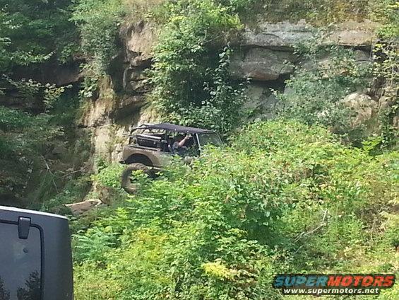 Off-road vehicle climbing a rocky, overgrown incline