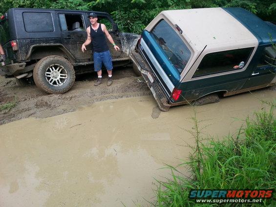 1996 Ford Bronco and Jeep Wrangler stuck in mud pit with a man standing between them