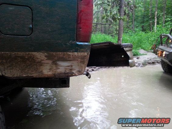 Rear of green SUV in mud with another vehicle visible