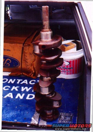 Ford crankshaft sitting in the trunk of a car, next to a Ford box and a bucket