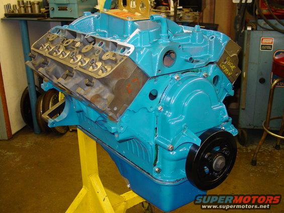 Turquoise V8 engine on a yellow stand, front view