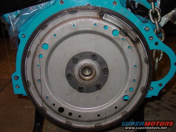 Engine flywheel with turquoise housing and Supermotors.net watermark