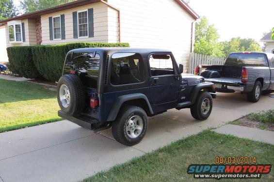 Dark blue 2000 Jeep Wrangler parked in driveway next to a gray pickup truck