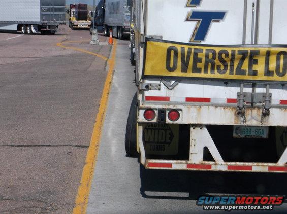 Rear view of a semi-trailer with 'Oversize Load' banner and license plate 699-6GA