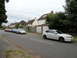 1999 Ford Fairlane - A white Subaru Impreza hatchback is parked on the right side of a street, with several other cars lined up on the left.