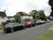 1999 Ford Fairlane - Multiple vehicles are parked along a residential street with houses in the background.