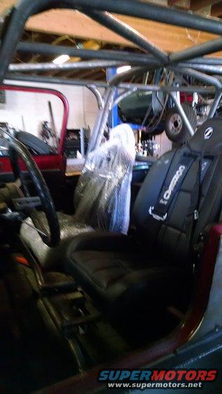 Interior of a Jeep with racing seats and roll cage. "Crower" visible on seat harness