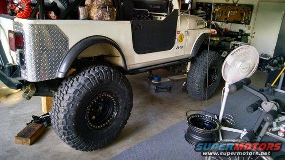 White 1985 Jeep CJ7 side view with large tires and diamond plate rear quarter panel