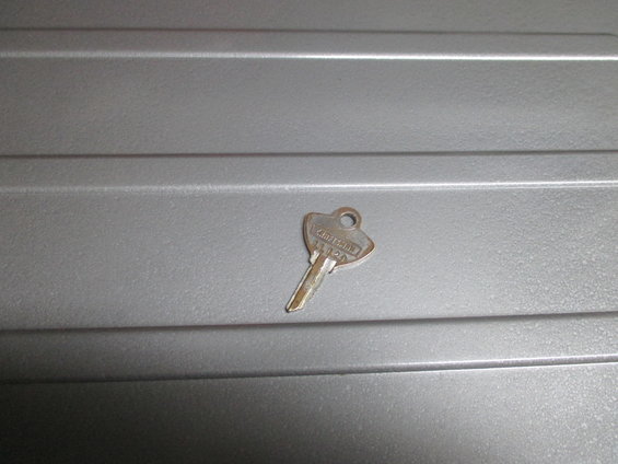 key with 'CRAFTSMAN 1120' stamped on it, lying on a gray textured surface