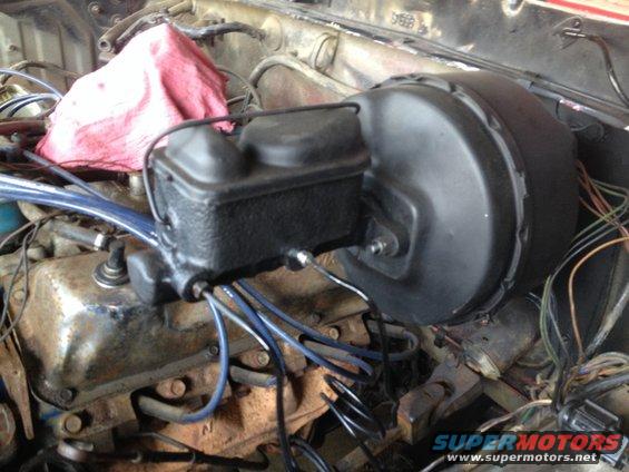 Brake booster and master cylinder assembly in engine bay with red rag on engine